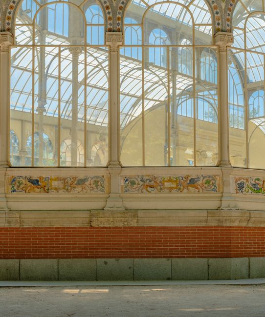 An outdoor covered platform at Crystal Palace Station featuring a large glass and metal roof structure with intricate decorative ironwork. The platform has a smooth concrete surface with visible shado